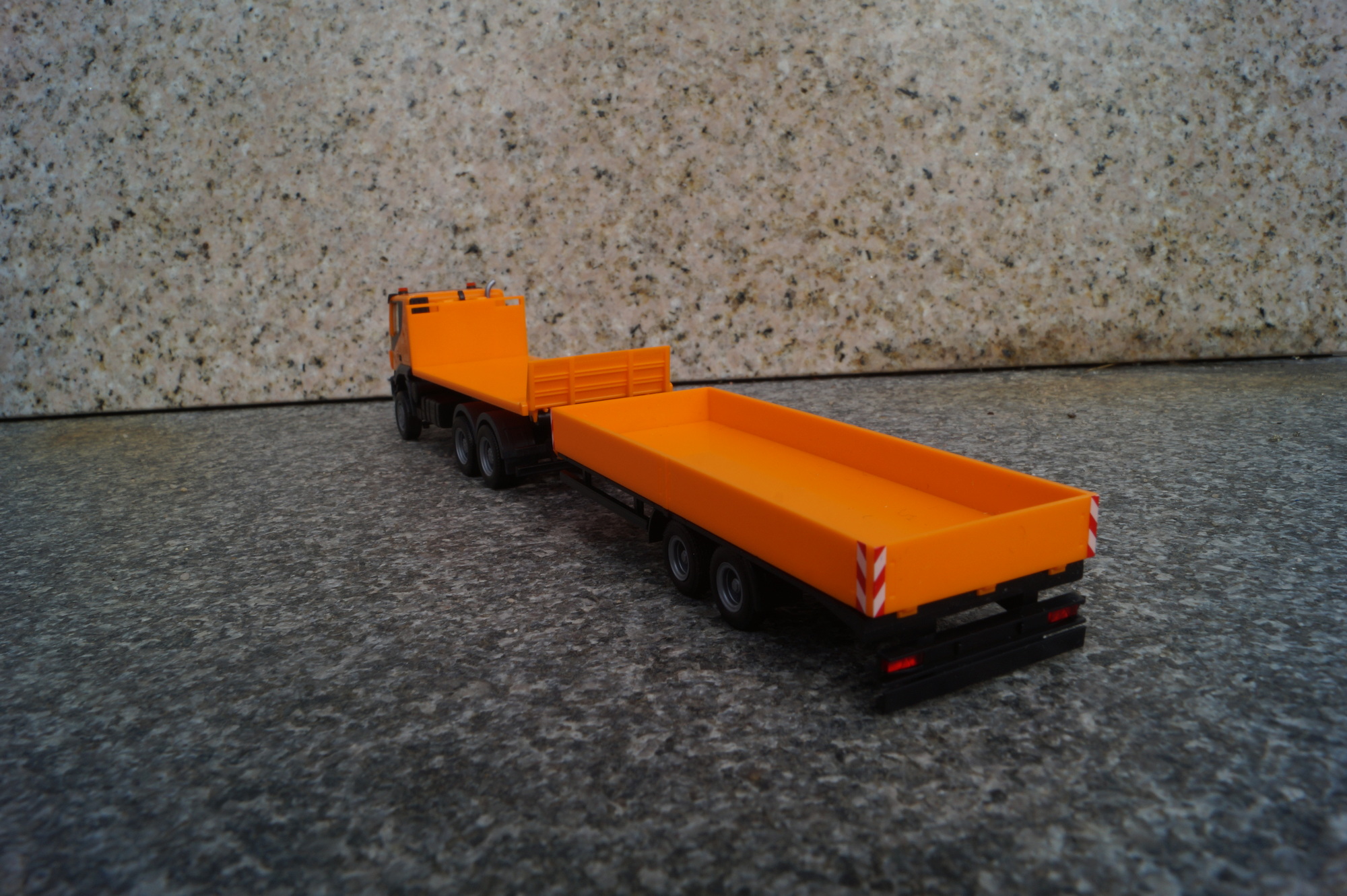311595 - Herpa - Iveco Trakker 6x6 Abrollflat-LKW mit Tieflade-Anhänger, kommunal orange